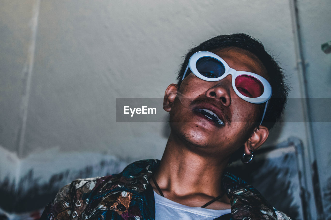 Portrait of young man wearing 3-d glasses while smoking cigarette