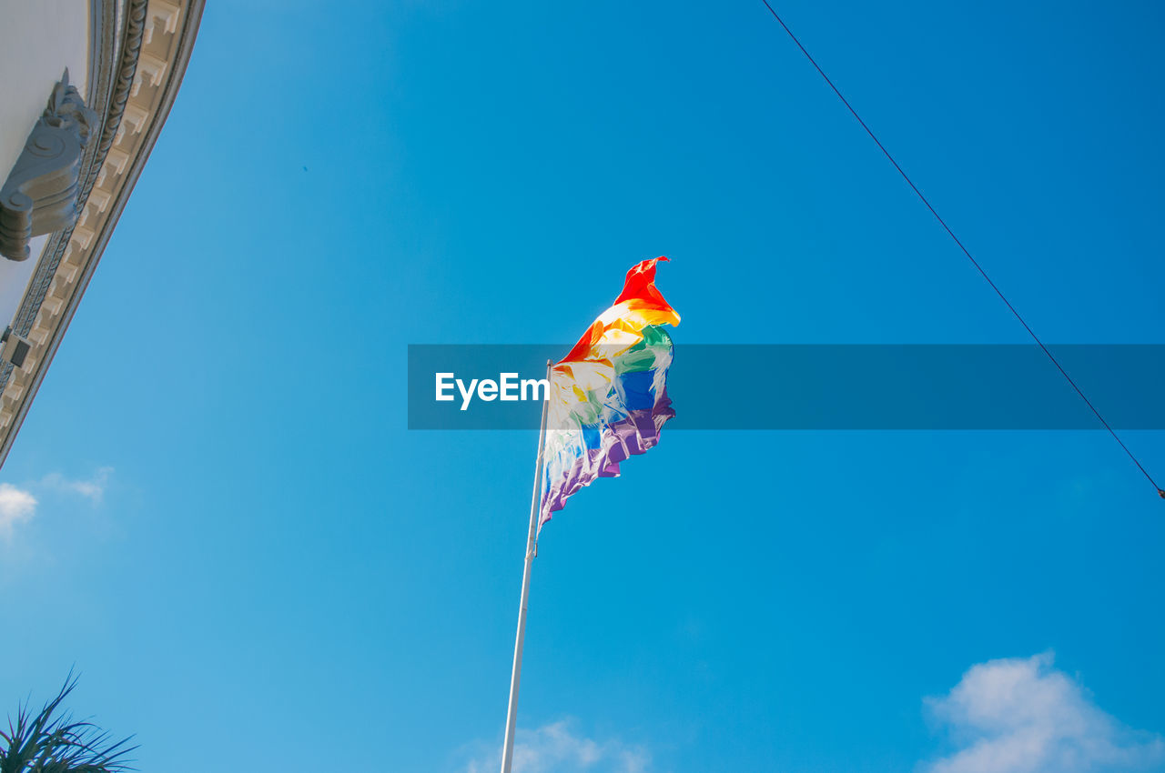 Low angle view of rainbow flag against sky