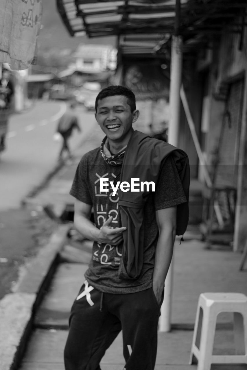 Cheerful young man standing in city