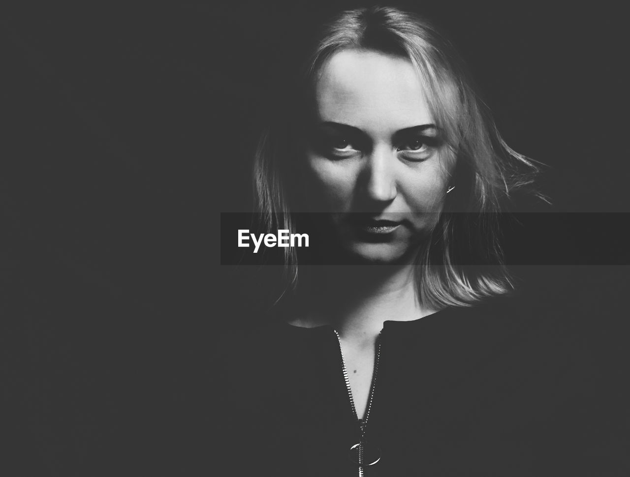 Close-up of young woman against black background