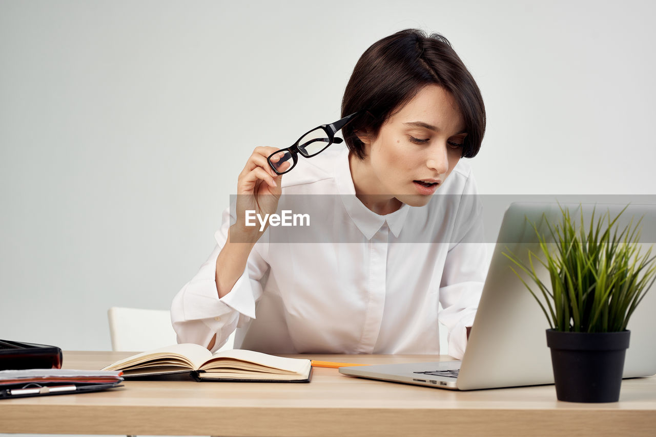 Young woman using mobile phone while sitting on table