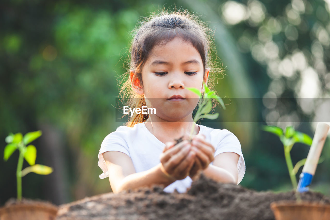 Close-up of girl holding plant in hand outdoors