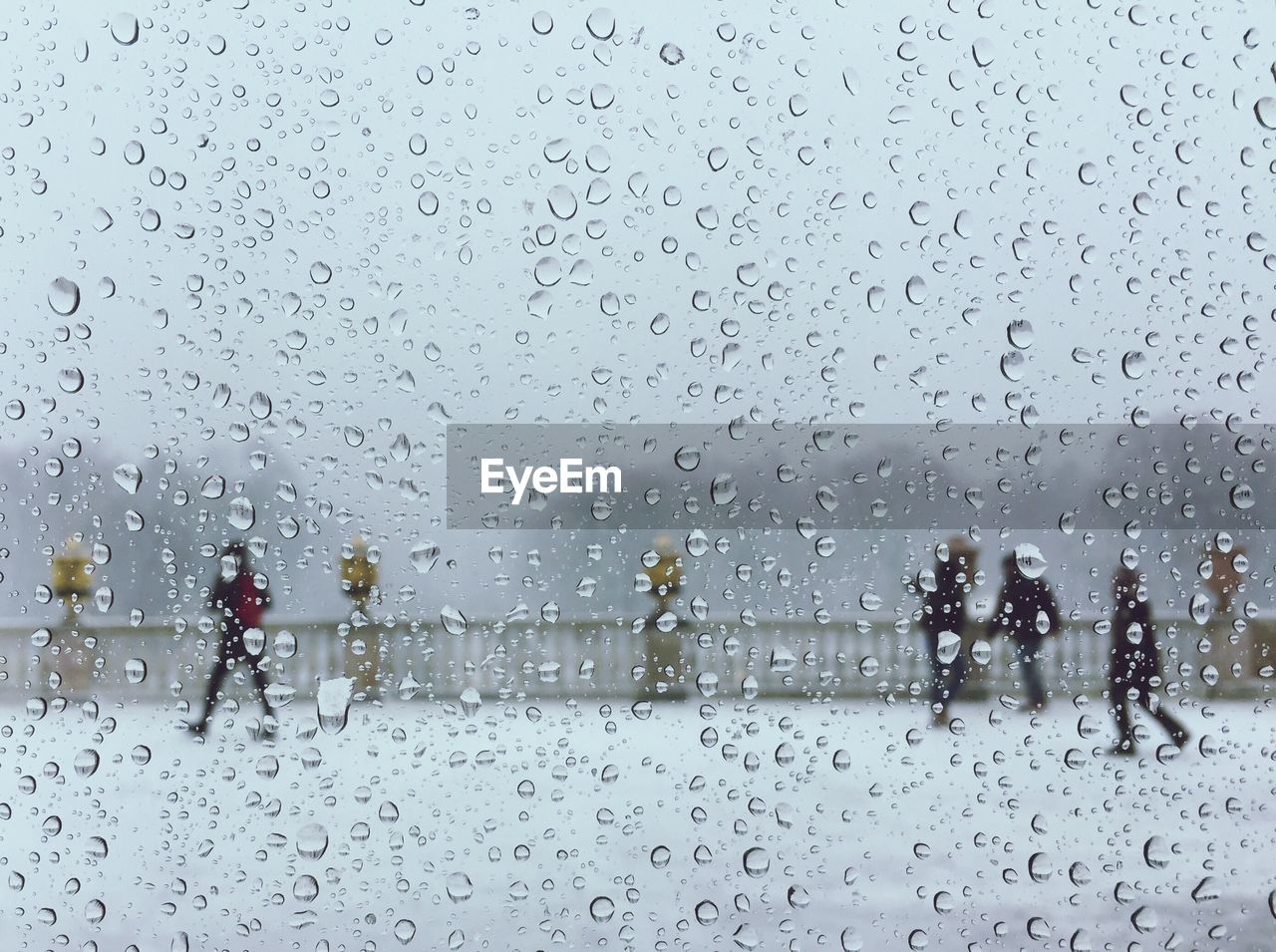 Dew drops on the window surface with the background of people outside and snow