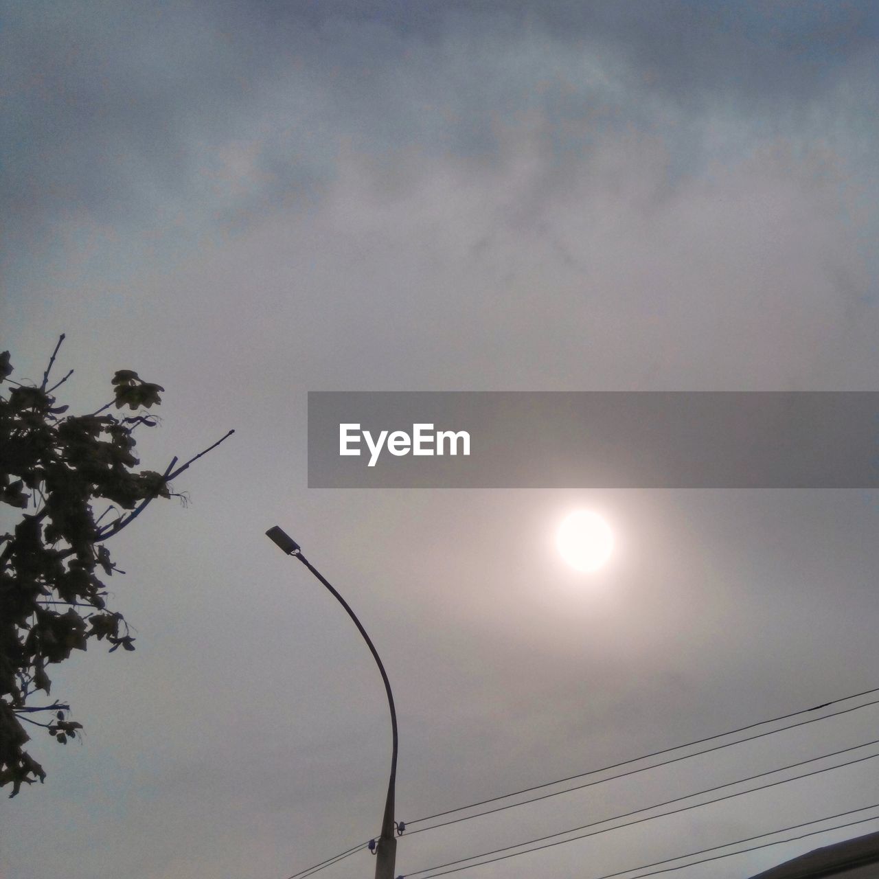 HIGH SECTION OF STREET LIGHT AGAINST CLOUDS