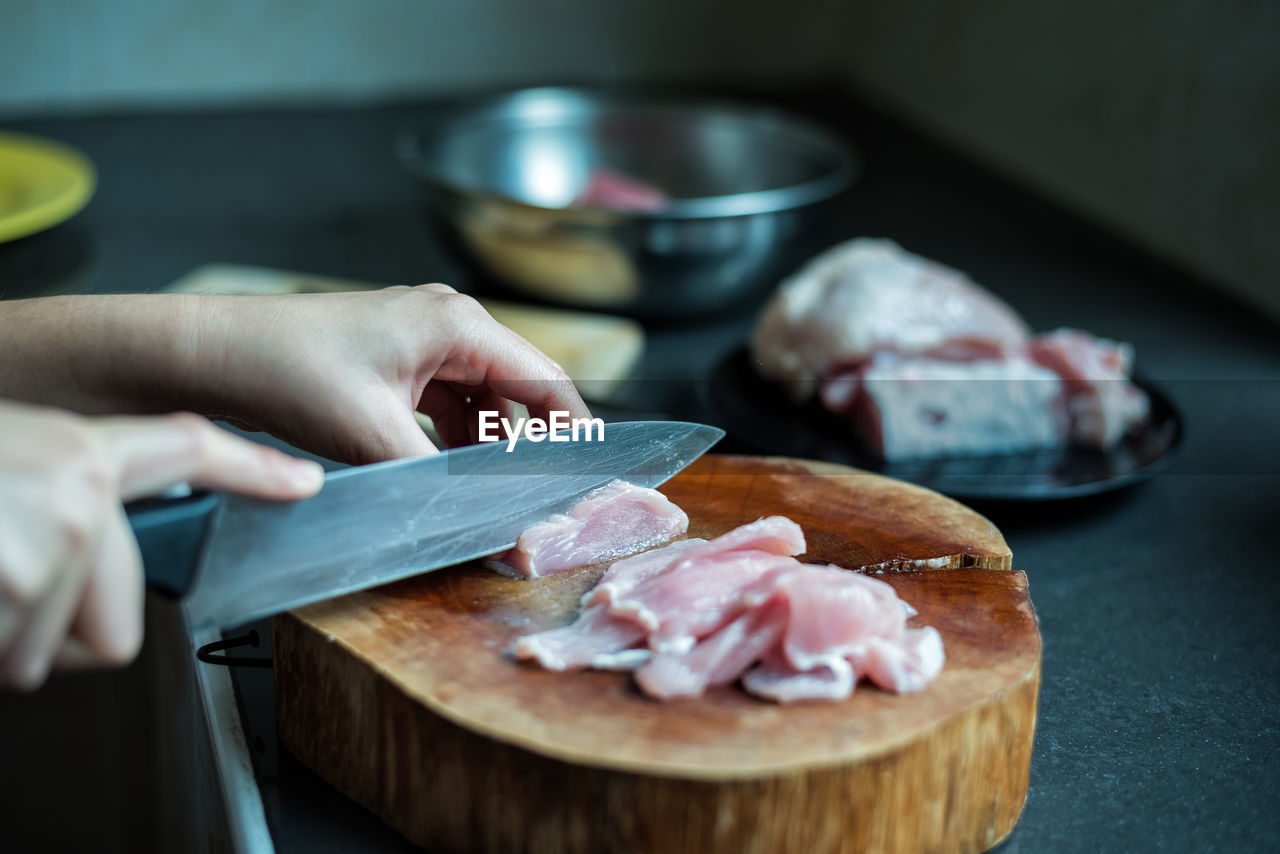 Cropped hands of woman cutting fish on wood