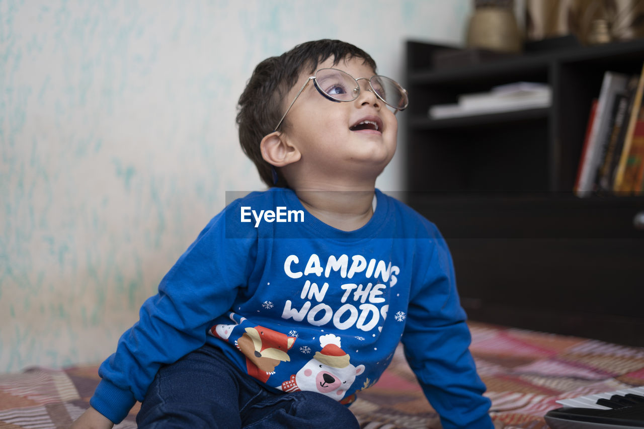 Cute boy wearing eyeglasses looking away while sitting at home