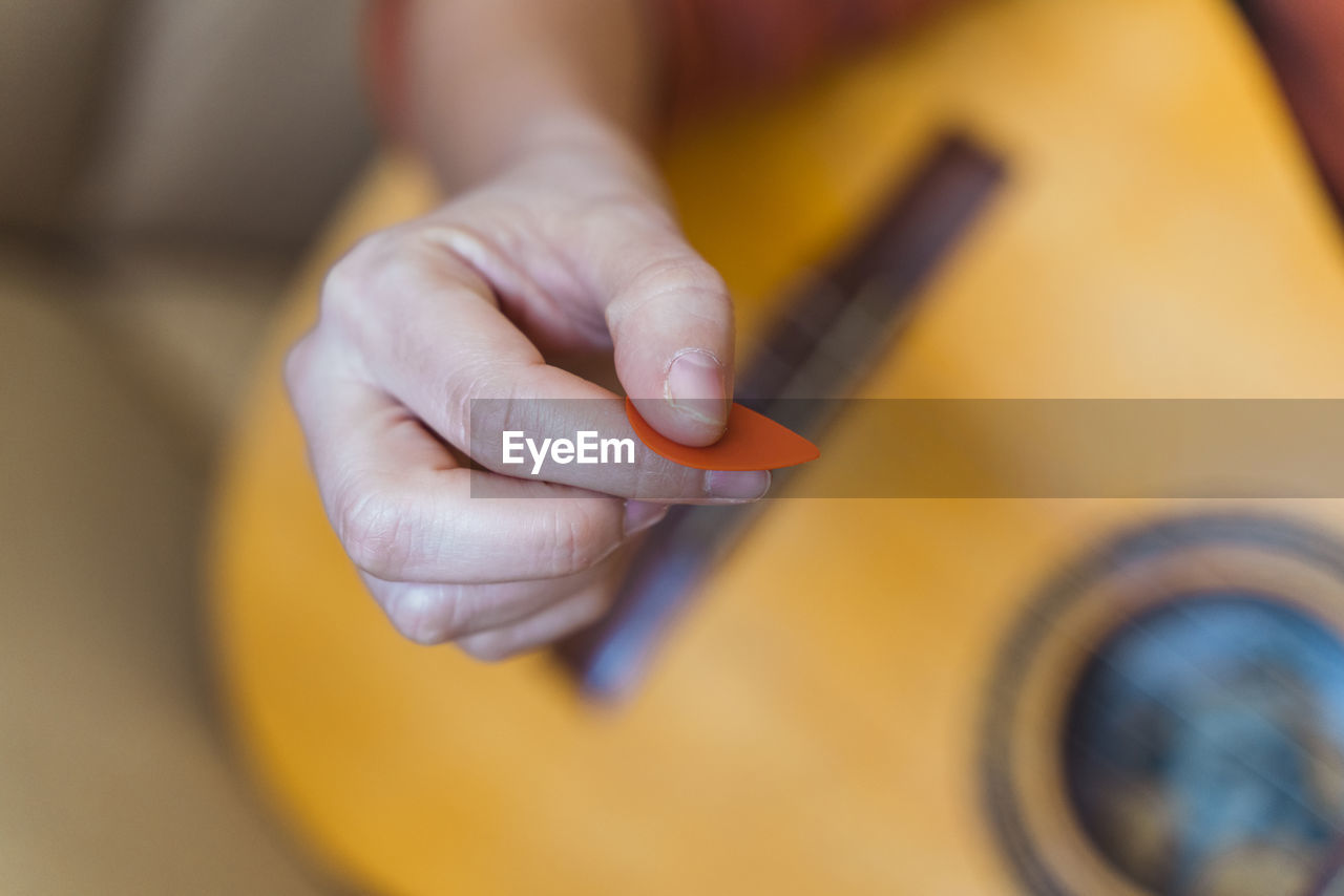 Cropped hand of woman playing guitar in home