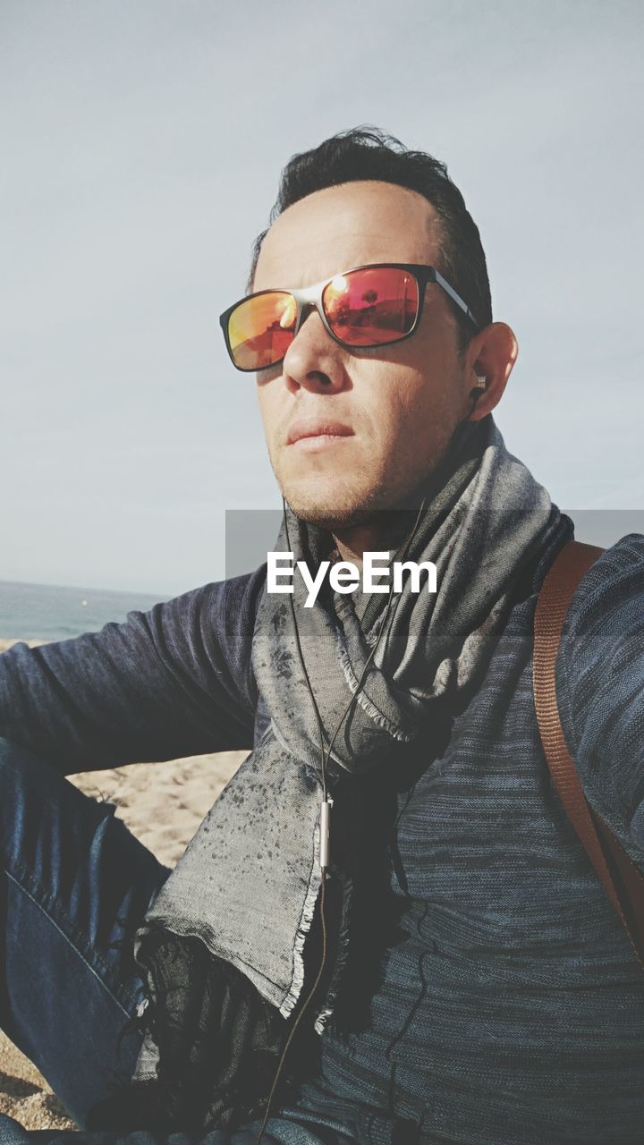 Young man wearing sunglasses while sitting at beach