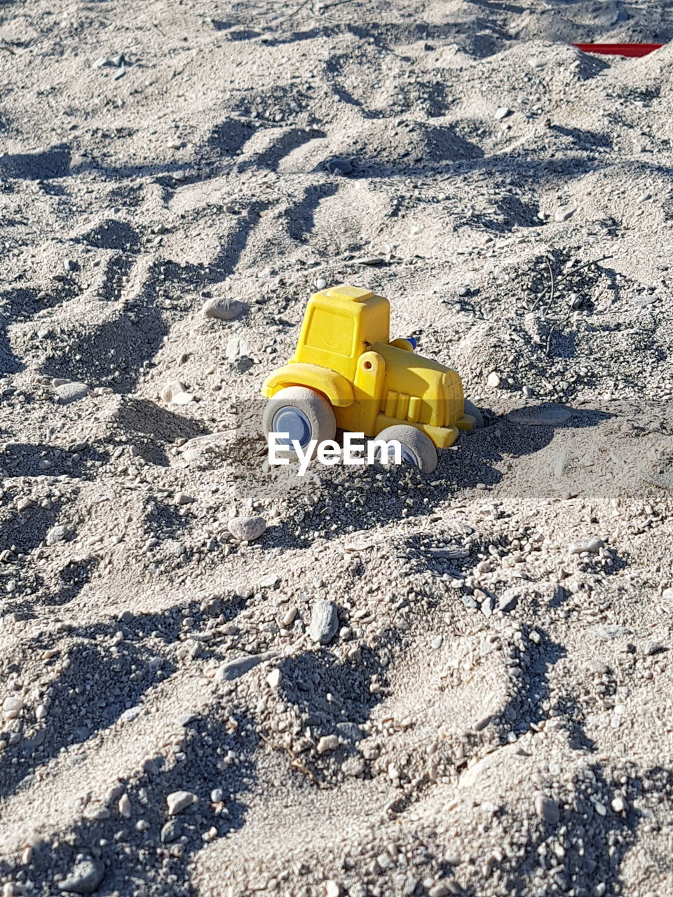 HIGH ANGLE VIEW OF TOY CAR ON SAND