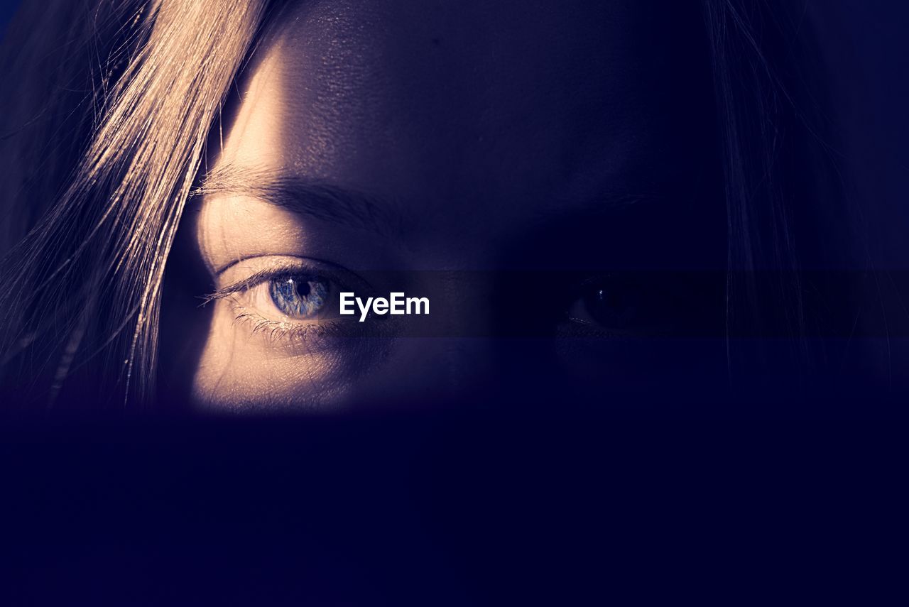 Portrait shot of beautiful girl with blue eyes standing in the shadows