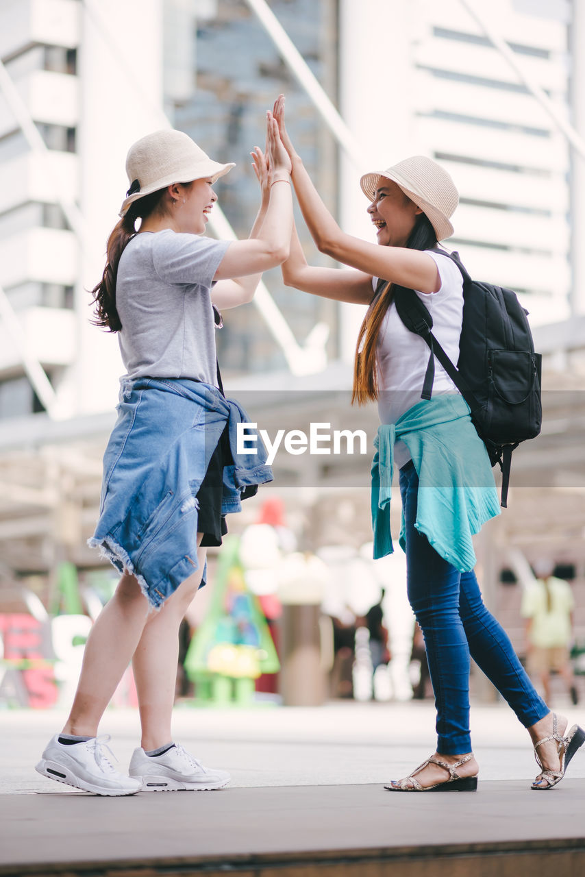 Tourists doing high five while standing in city