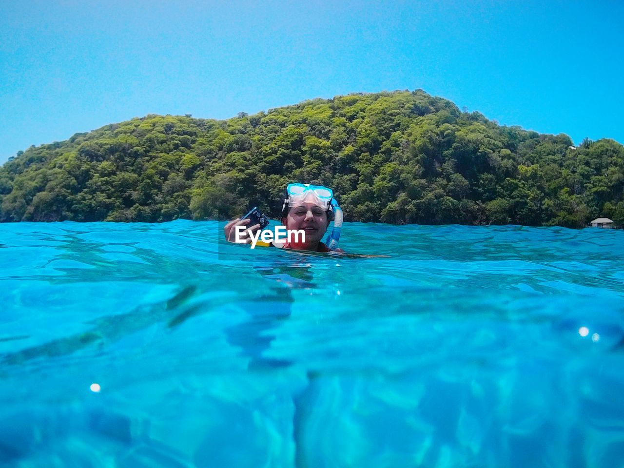 Young woman swimming in sea against clear blue sky