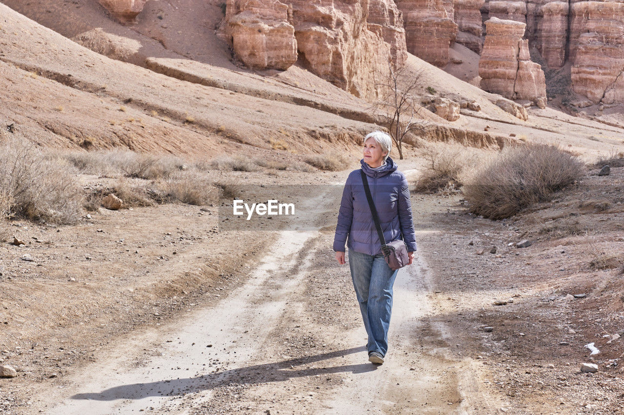 Senior caucasian woman tourist walking along charyn canyon, national natural park in kazakhstan.