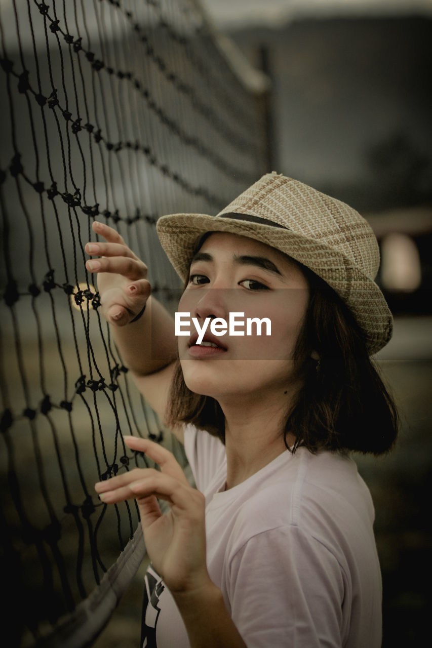 Young woman standing by sports net