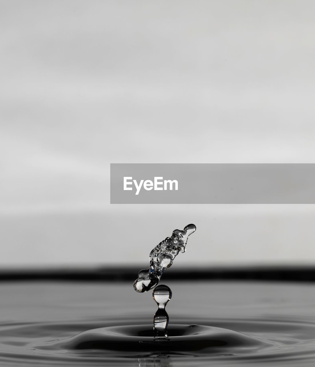 CLOSE-UP OF DROP FALLING ON WATER IN CONTAINER