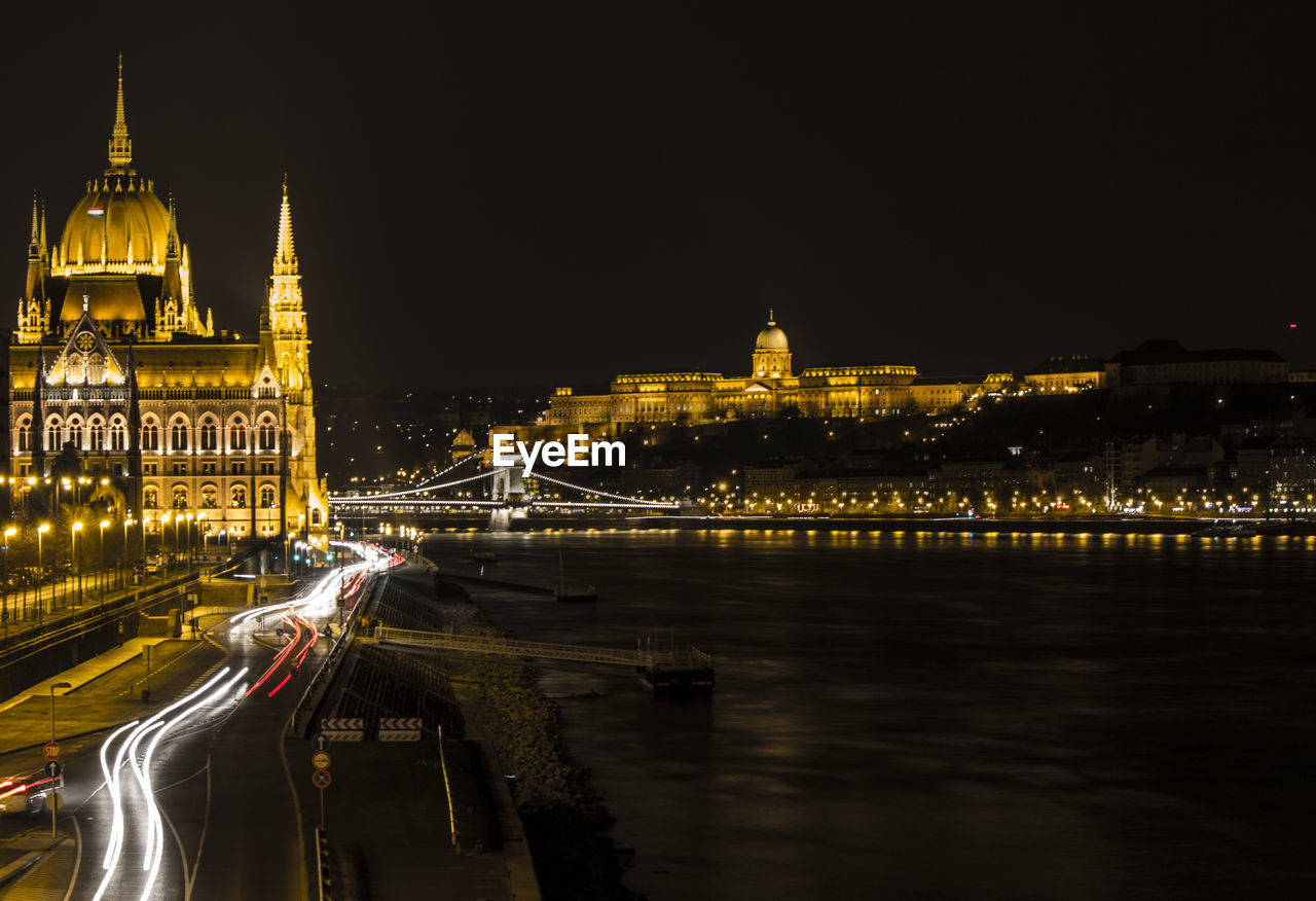 River amidst illuminated hungarian parliament building and buda castle against clear sky at night