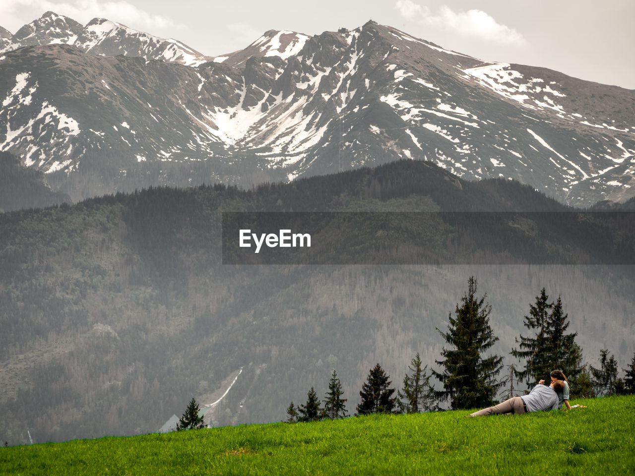 Couple relaxing on green landscape by mountains