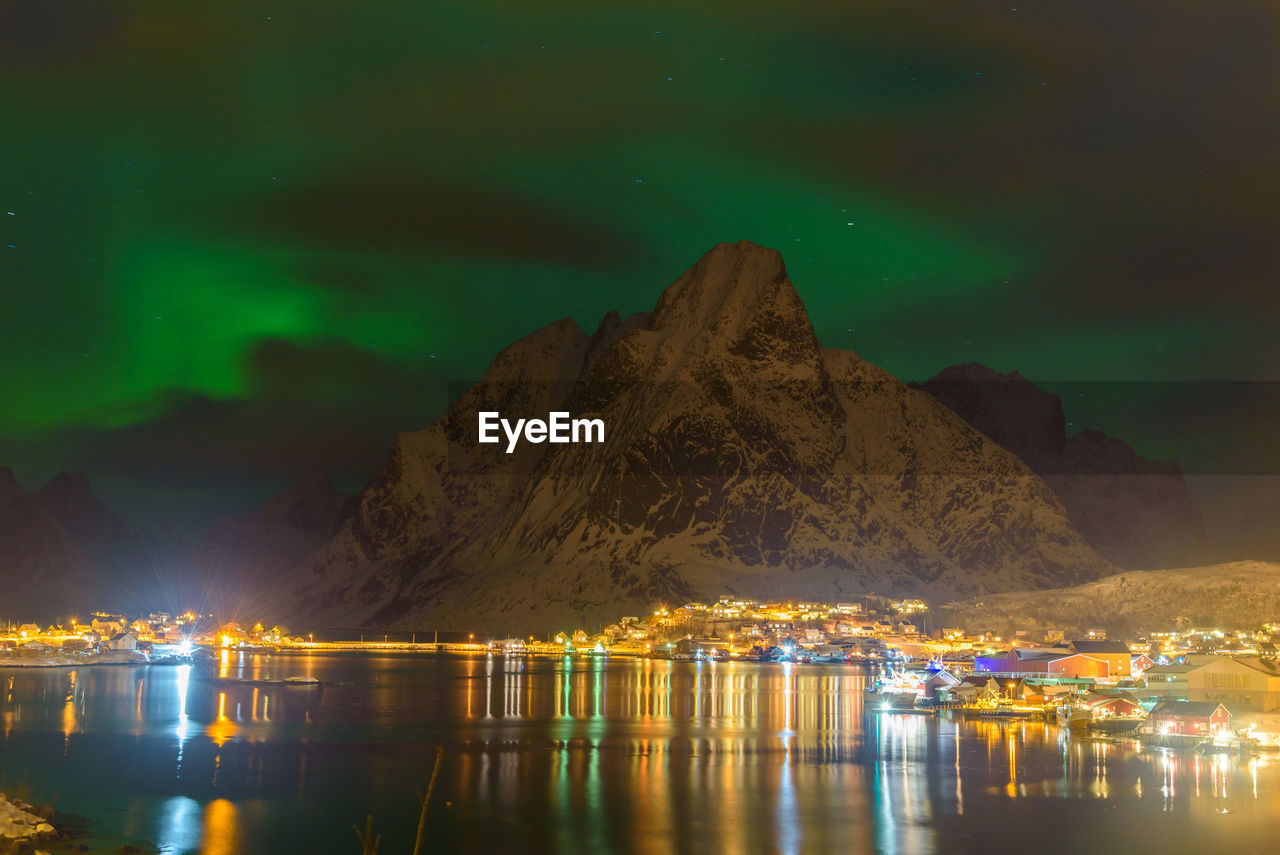 Scenic view of lake by illuminated mountain against sky at night