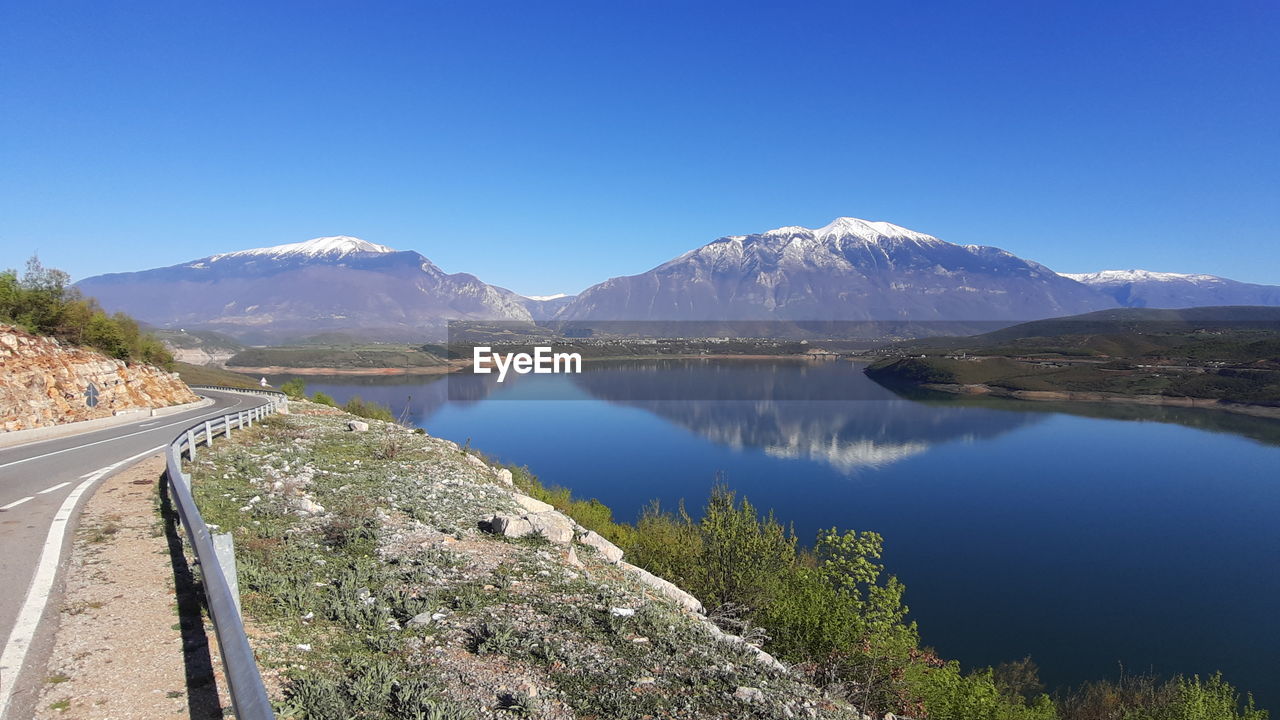 Panoramic view of lake and mountains against clear blue sky