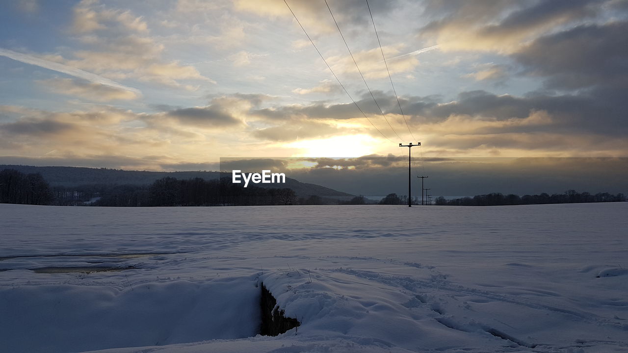 Scenic view of frozen landscape against sky during sunset