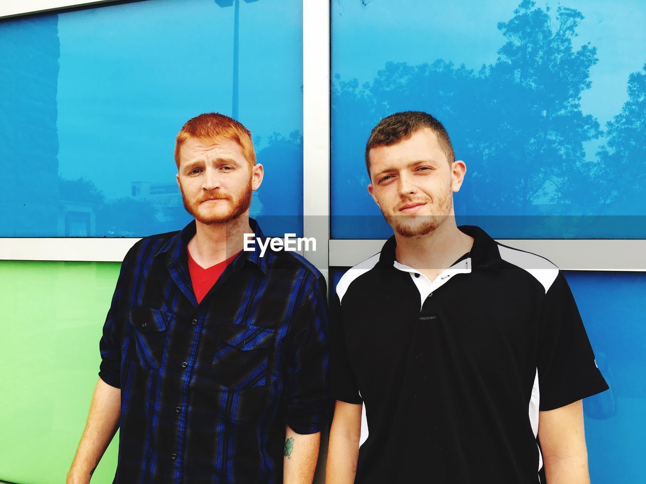 Portrait of friends standing against glass wall