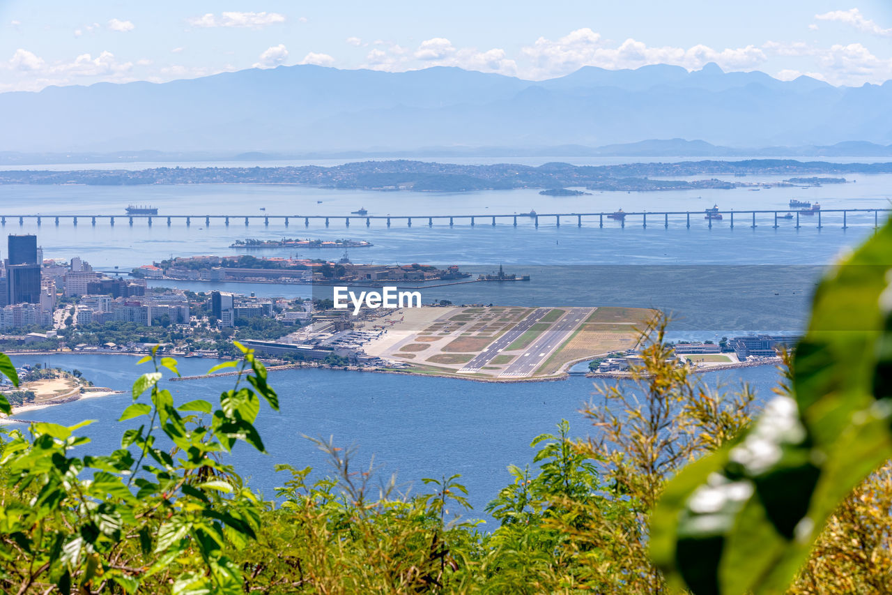 high angle view of cityscape by sea against sky