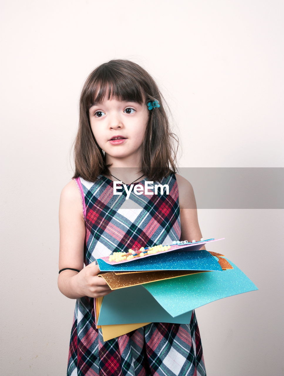 child, childhood, one person, portrait, education, studio shot, learning, women, indoors, cute, student, looking at camera, publication, female, pattern, white background, hairstyle, book, front view, brown hair, photo shoot, innocence, casual clothing, holding, emotion, clothing, waist up, long hair, copy space, smiling, standing, tartan, studying, school children, looking, happiness, sitting, fun, school, person