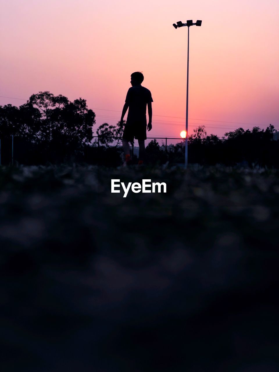 Silhouette man standing on street against sky during sunset