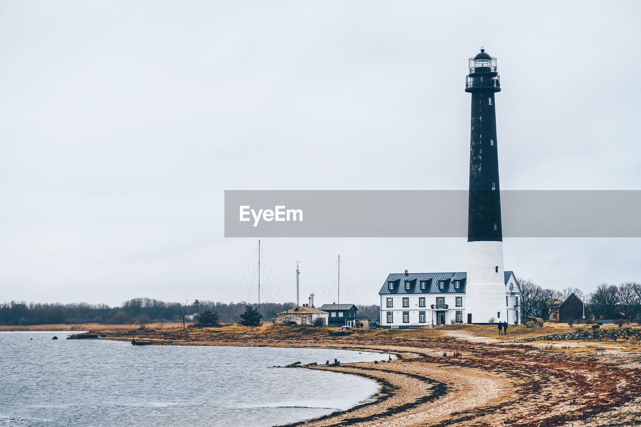 LIGHTHOUSE AMIDST BUILDINGS AND SKY