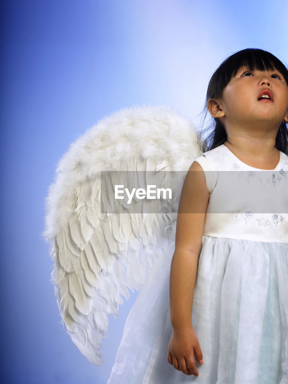 GIRL LOOKING AWAY WHILE STANDING ON WHITE BACKGROUND