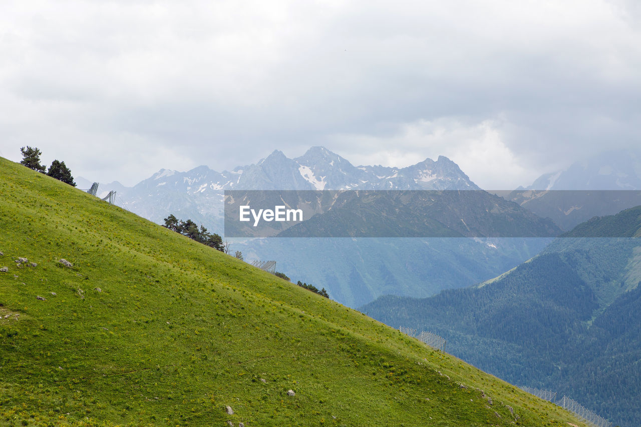 Green slope of a high mountain during a thunderstorm with clouds in the sky