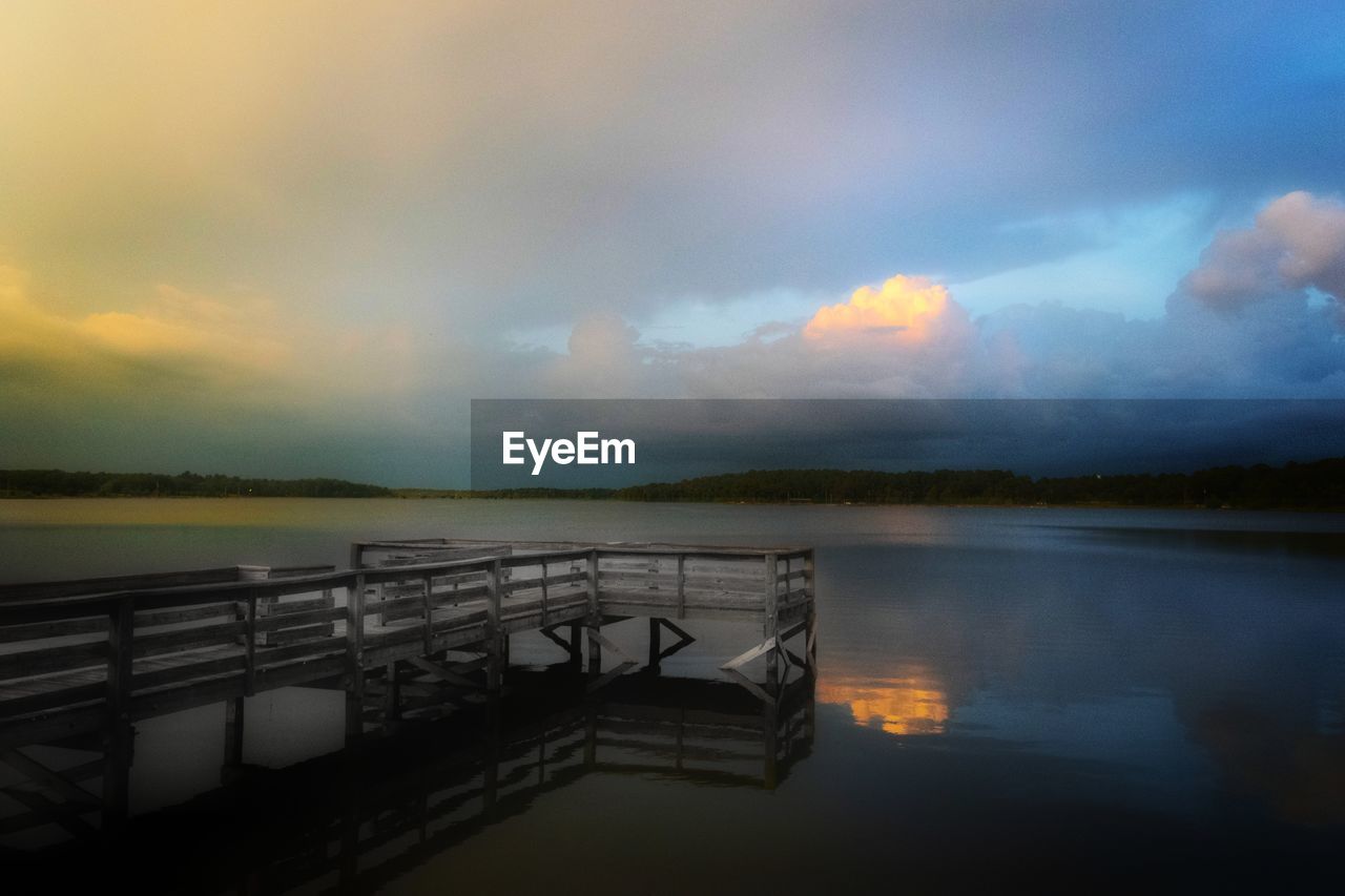 PIER OVER LAKE AGAINST SKY AT SUNSET