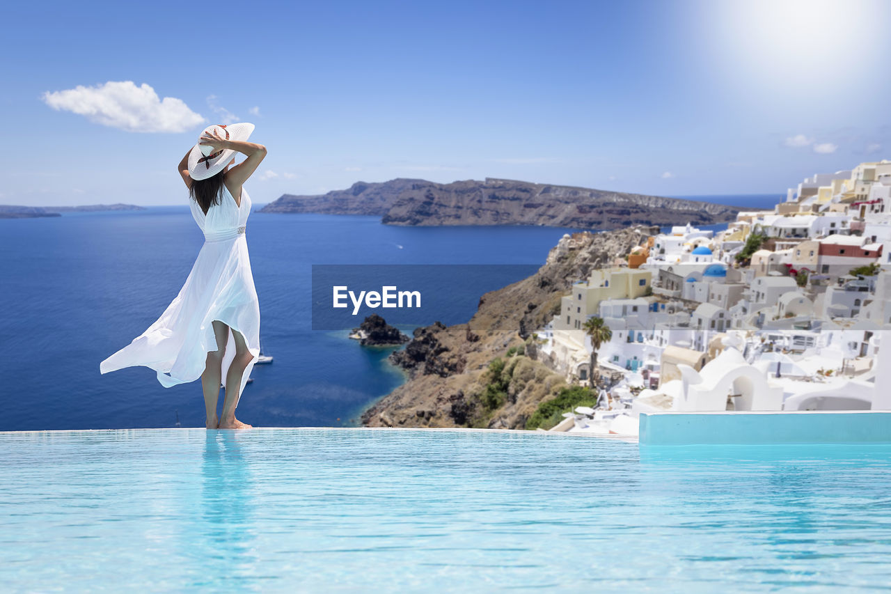 Rear view of woman standing in sea against sky