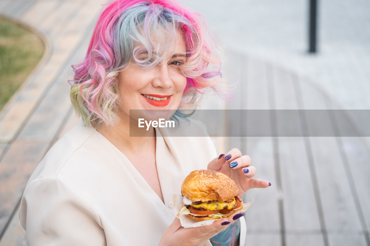 Woman holding burger outdoors