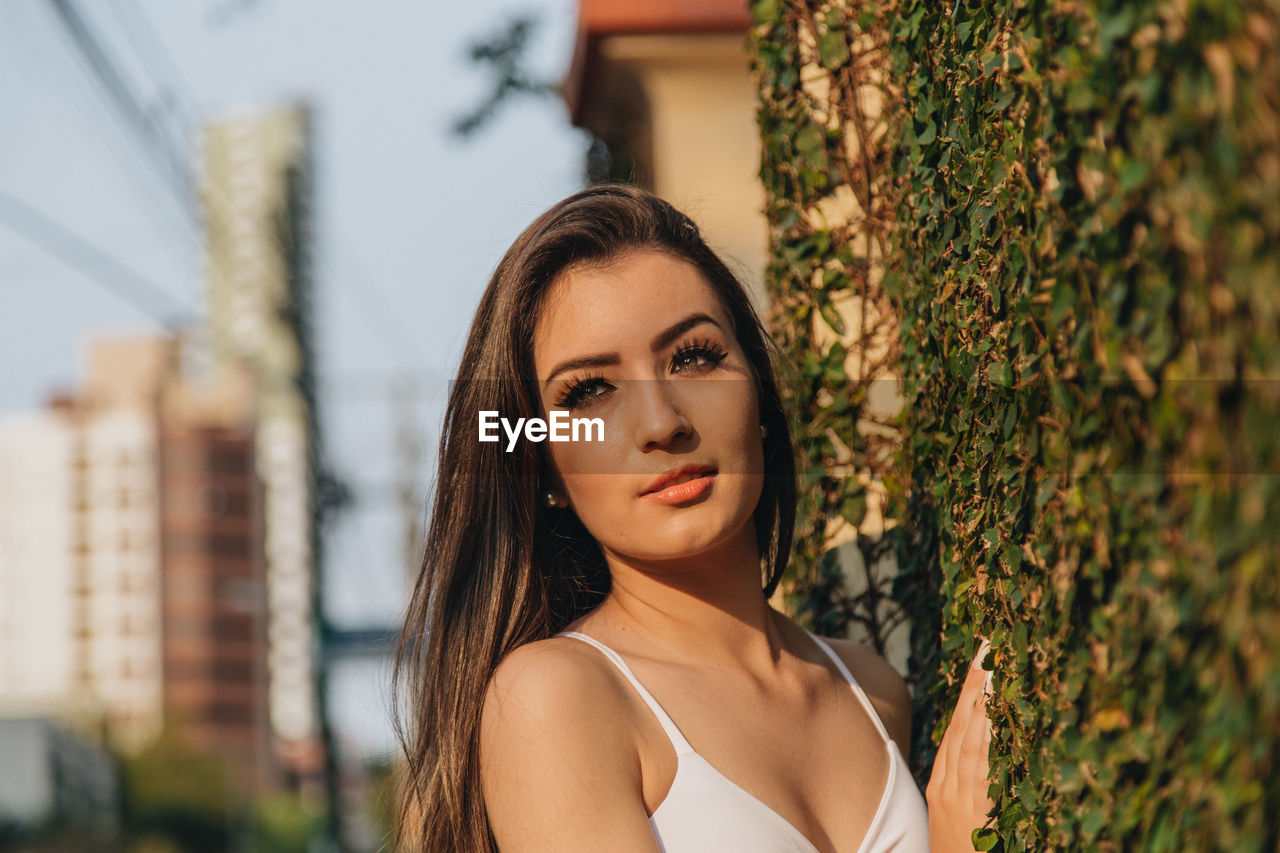 Close-up of beautiful woman standing against creeper wall