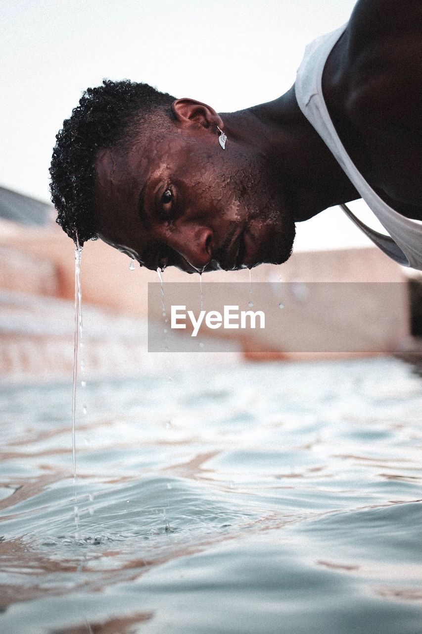 Portrait of young man washing head in pond