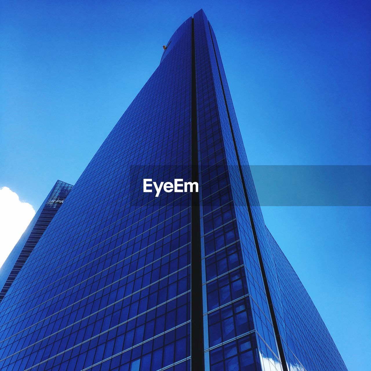 LOW ANGLE VIEW OF GLASS BUILDING AGAINST CLEAR BLUE SKY