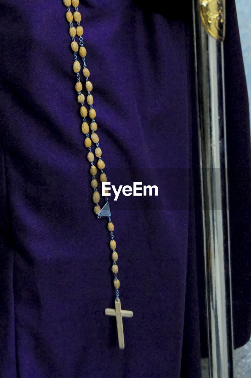 Midsection of person wearing crucifix necklace during holy week