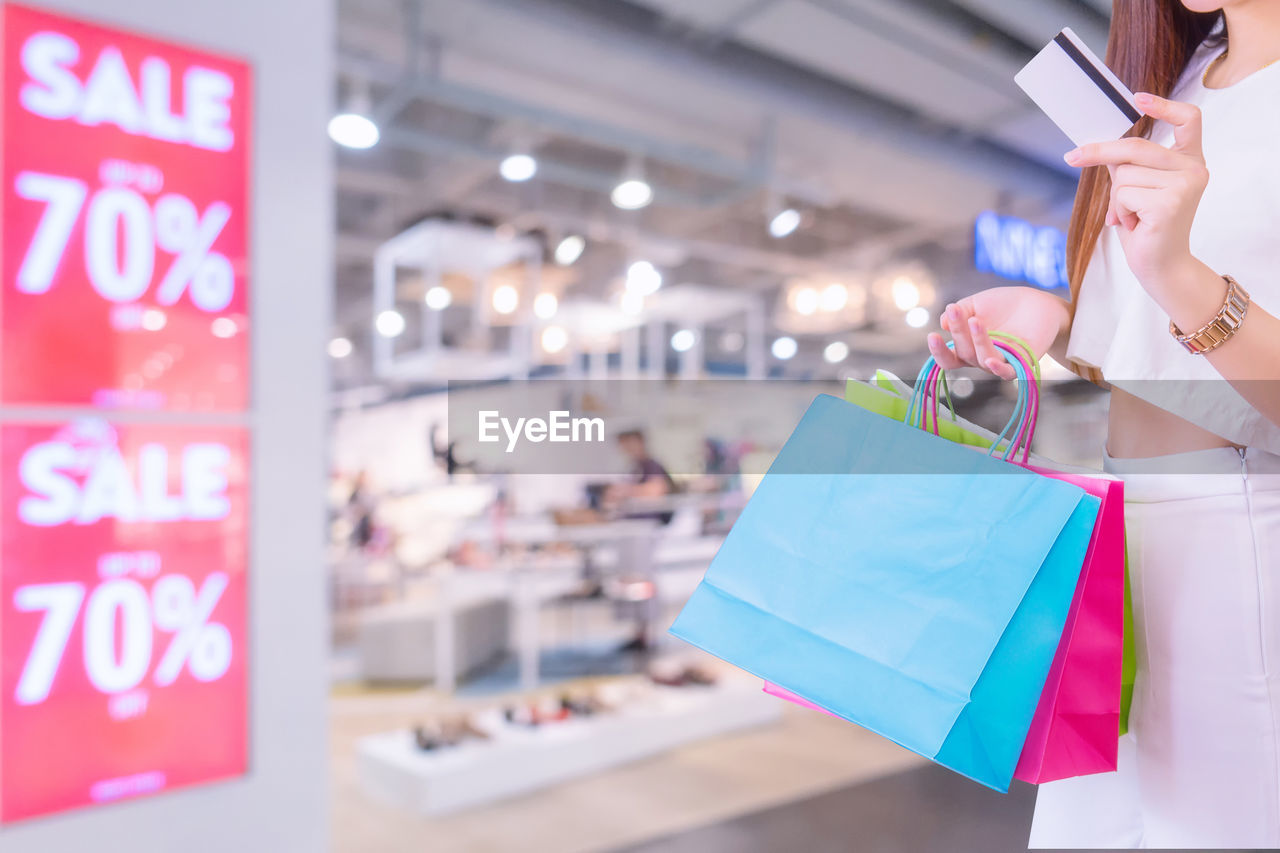 MIDSECTION OF WOMAN HOLDING SHOPPING MALL