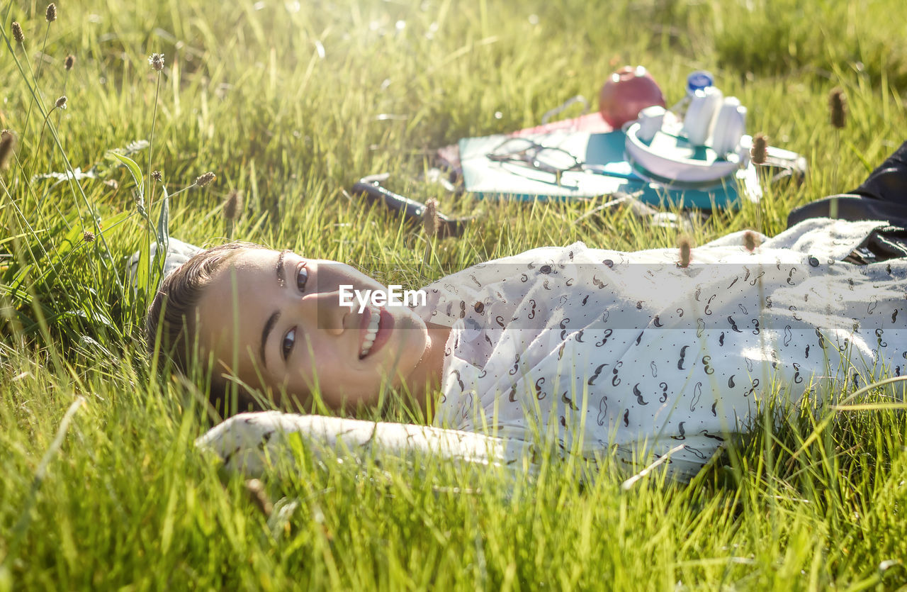 Portrait of young woman while lying on grass at park