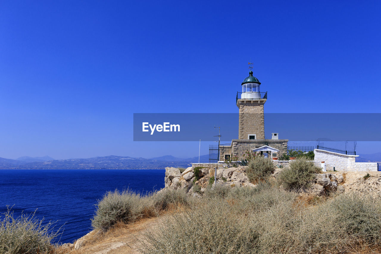 An old stone lighthouse stands on the high cape of malagavi against the backdrop of the blue sea