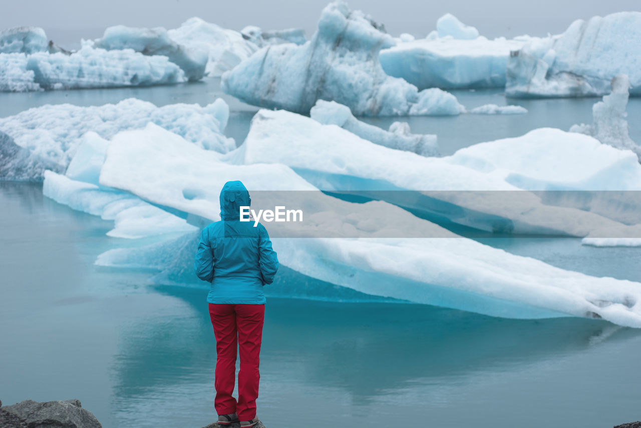 Rear view of woman standing by sea during winter