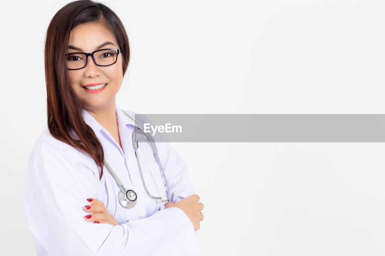 Portrait of smiling doctor standing against white background