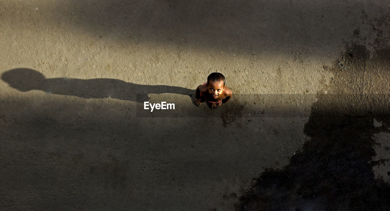 High angle view of smiling shirtless boy standing on road