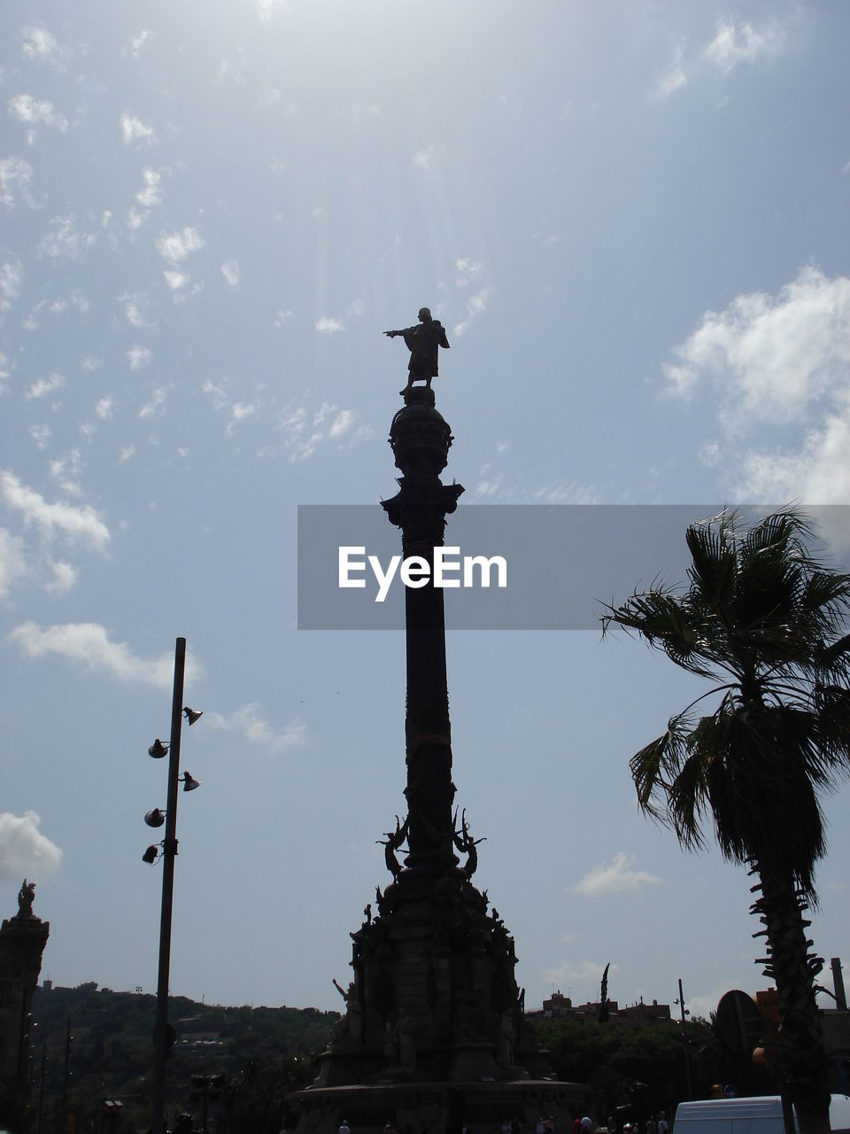 Low angle view of silhouette monument against cloudy sky on sunny day