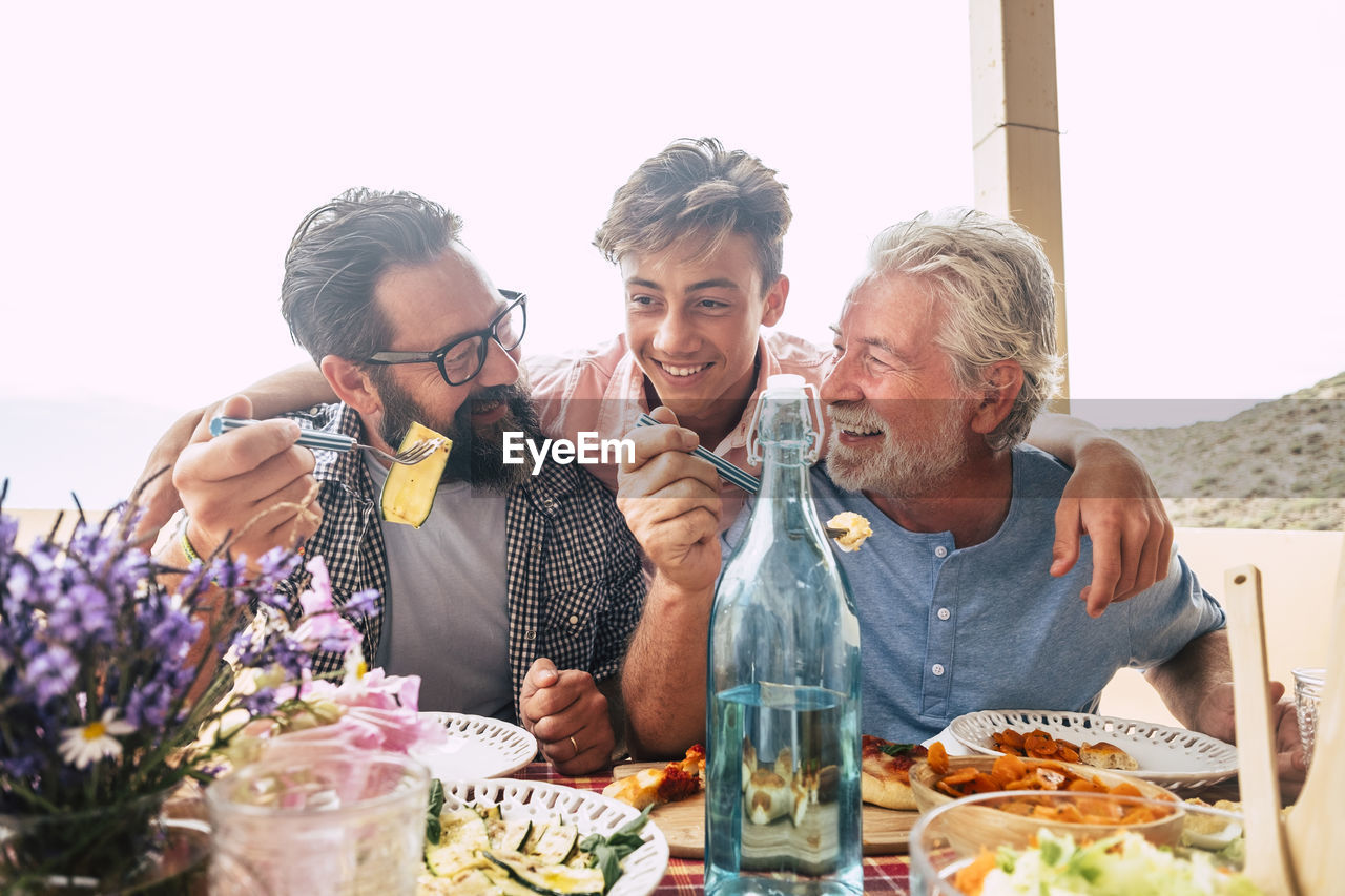 Cheerful family eating food while sitting at restaurant