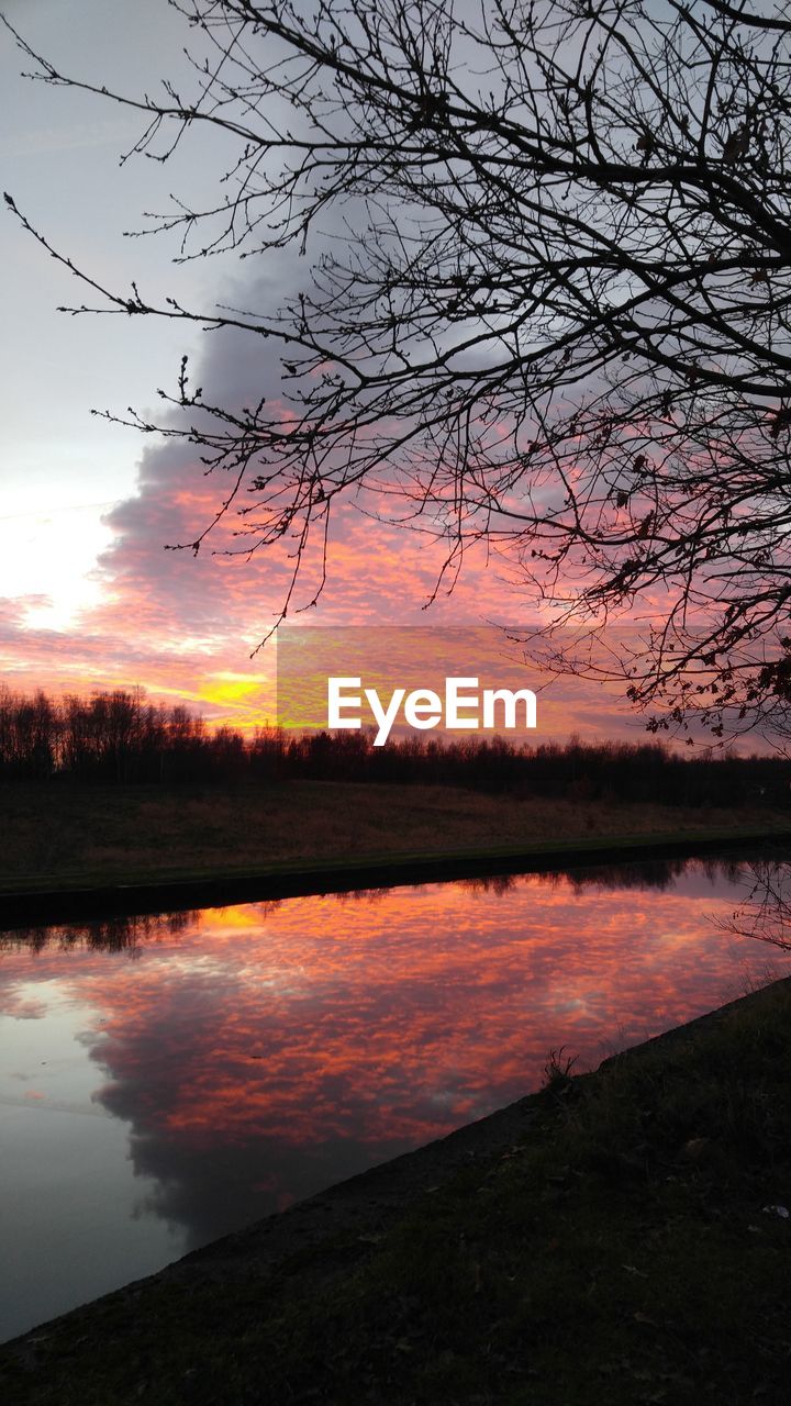 SCENIC VIEW OF LAKE AGAINST CLOUDY SKY DURING SUNSET