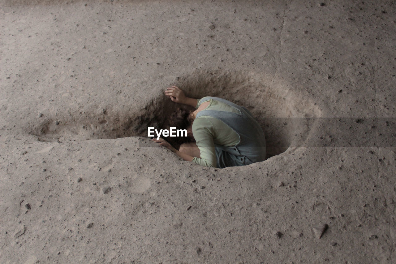 High angle view of girl sitting in hole
