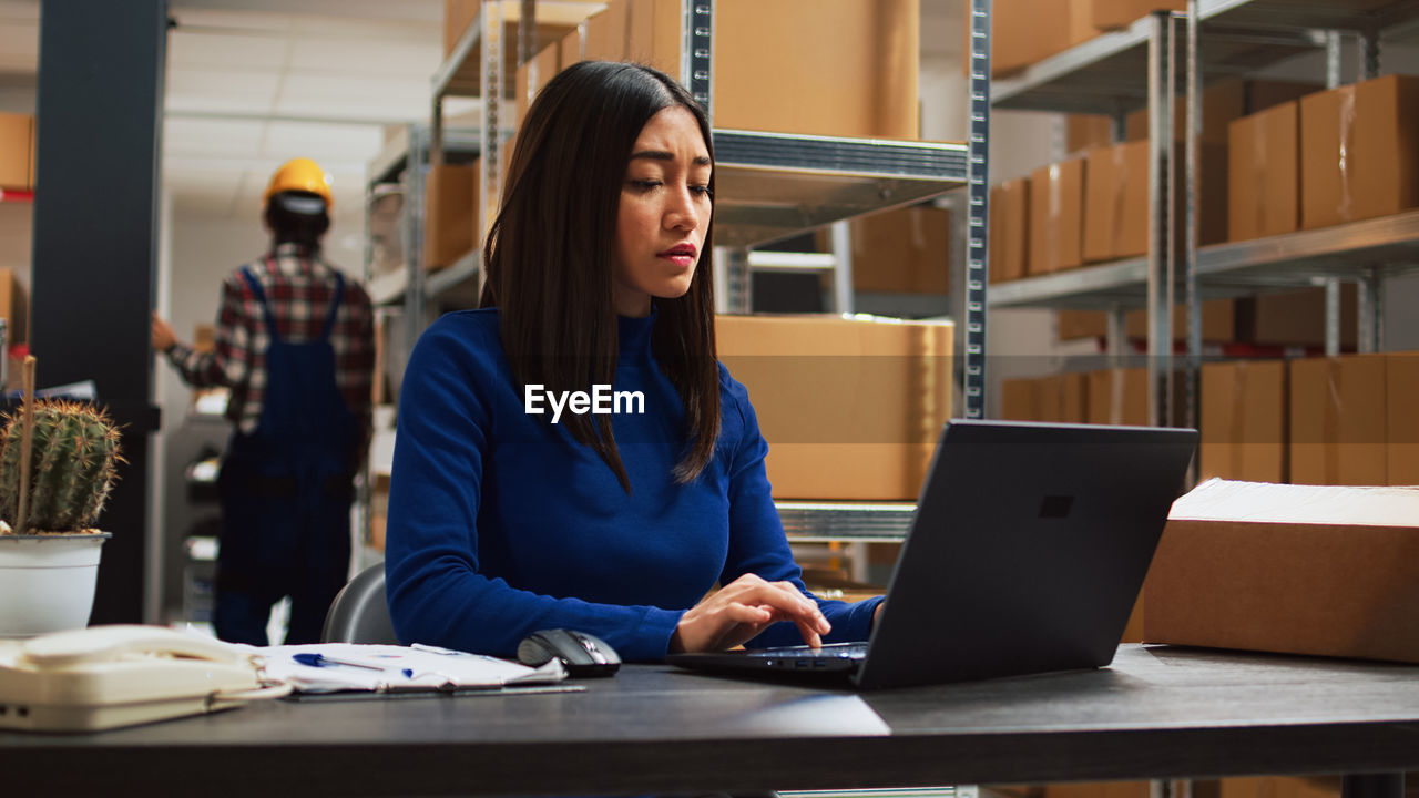 young businesswoman using laptop while sitting at office