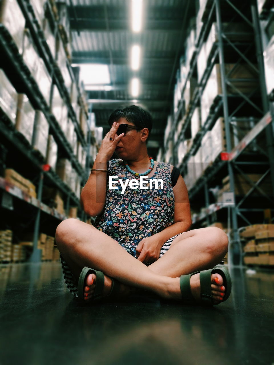 Full length of woman sitting amidst shelves